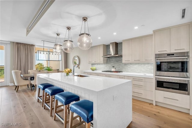 kitchen featuring a sink, tasteful backsplash, double oven, wall chimney exhaust hood, and light countertops