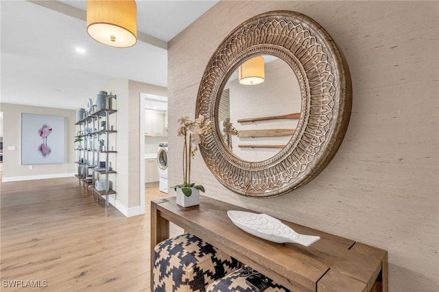 corridor featuring washer / clothes dryer, wood finished floors, and baseboards