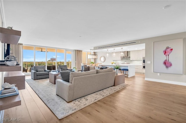 living room featuring light wood finished floors, baseboards, and expansive windows