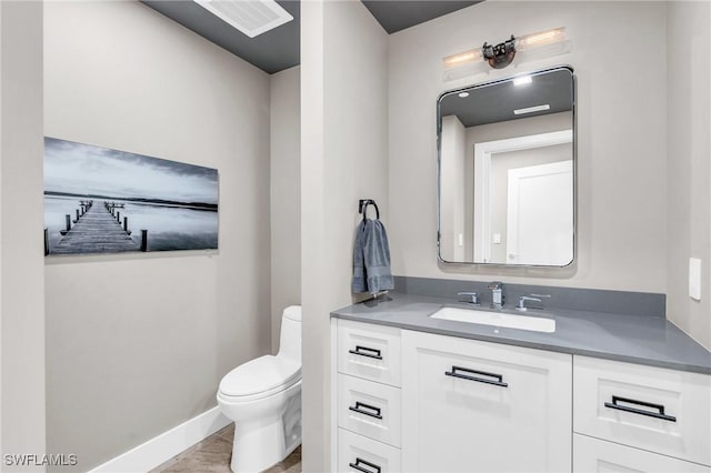 half bathroom featuring visible vents, toilet, vanity, and baseboards