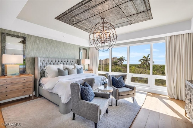 bedroom featuring a notable chandelier, a tray ceiling, and wood finished floors