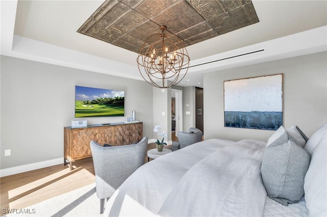 bedroom featuring wood finished floors, baseboards, an ornate ceiling, a raised ceiling, and a chandelier