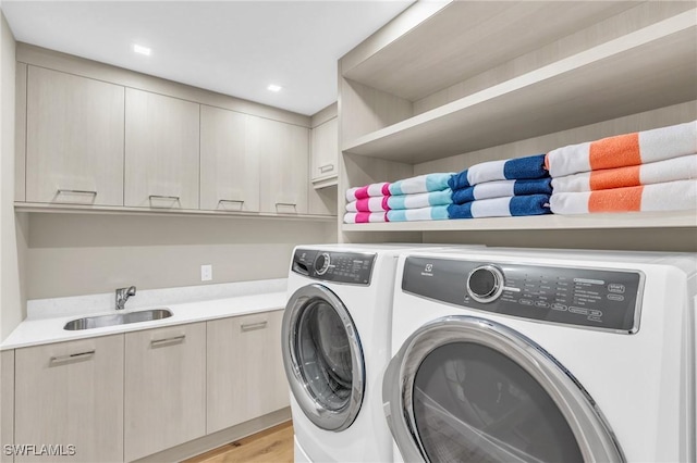 laundry area featuring washer and clothes dryer, recessed lighting, light wood-style flooring, cabinet space, and a sink