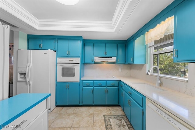 kitchen with white appliances, a tray ceiling, crown molding, under cabinet range hood, and a sink