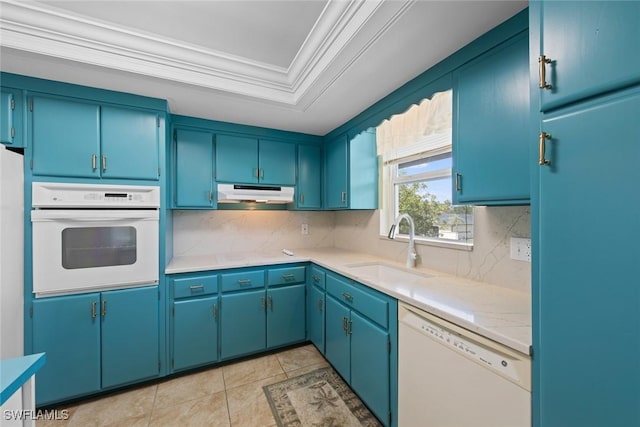 kitchen with a raised ceiling, light countertops, a sink, white appliances, and under cabinet range hood