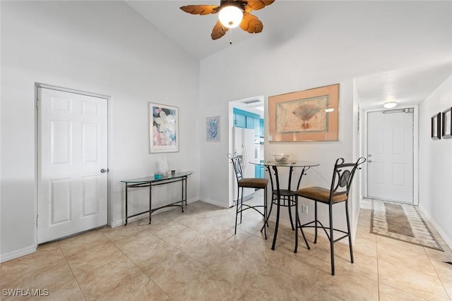 dining room featuring light tile patterned floors, ceiling fan, baseboards, and high vaulted ceiling