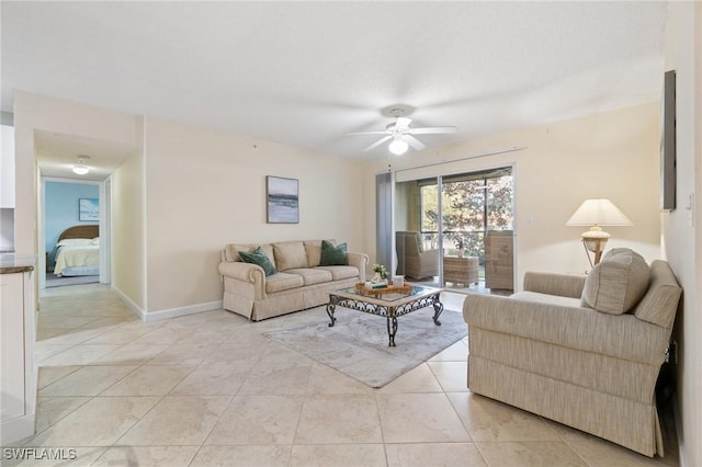 living area featuring light tile patterned floors, a ceiling fan, and baseboards