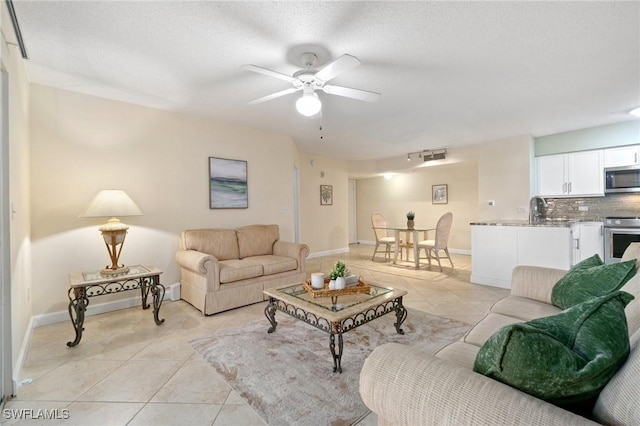 living room with a textured ceiling, baseboards, and light tile patterned floors