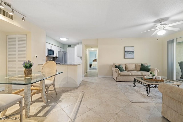 living area with visible vents, light tile patterned flooring, ceiling fan, a textured ceiling, and baseboards