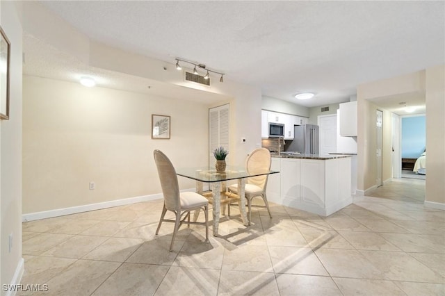 dining room featuring a textured ceiling, light tile patterned floors, and baseboards