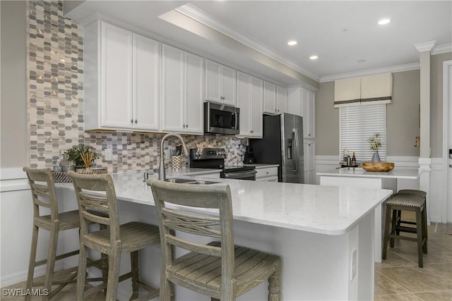 kitchen featuring crown molding, tasteful backsplash, appliances with stainless steel finishes, a sink, and a peninsula