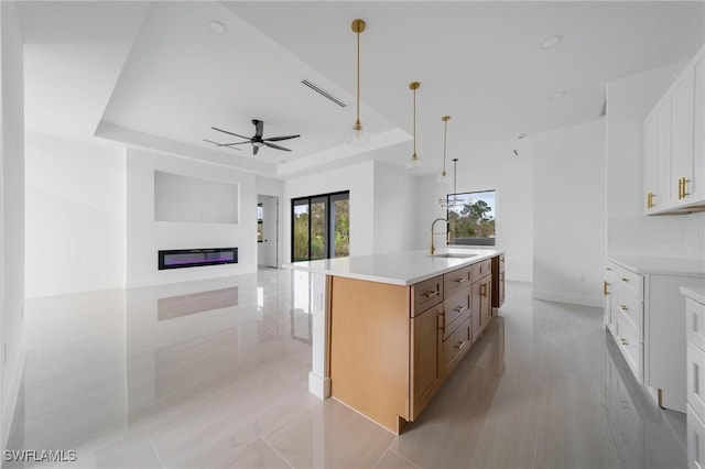 kitchen featuring a sink, white cabinets, open floor plan, light countertops, and a large island with sink