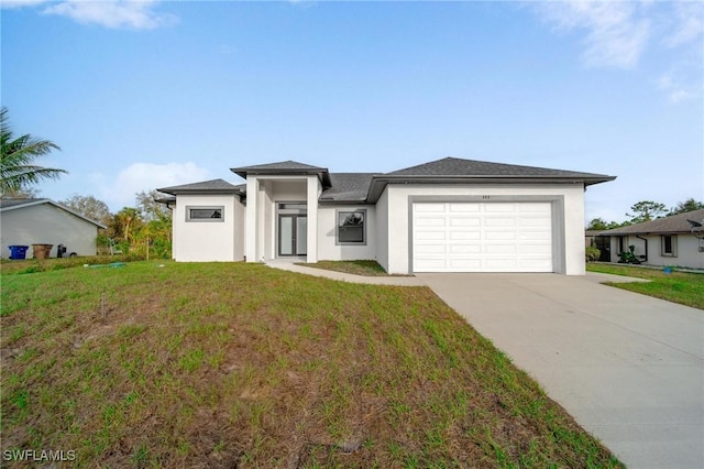 prairie-style house with a garage, concrete driveway, a front lawn, and stucco siding