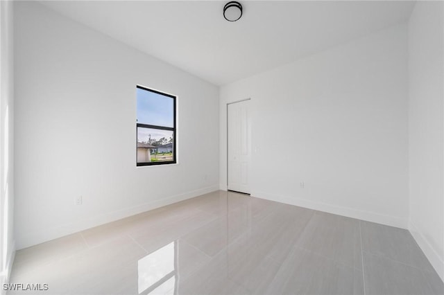 spare room with light tile patterned floors and baseboards