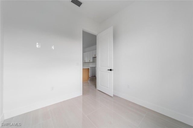 unfurnished room with light tile patterned floors, visible vents, and baseboards