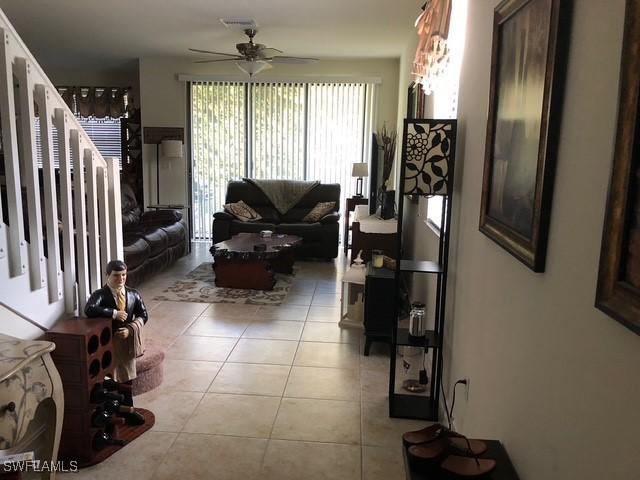 living area featuring light tile patterned floors, visible vents, and a ceiling fan