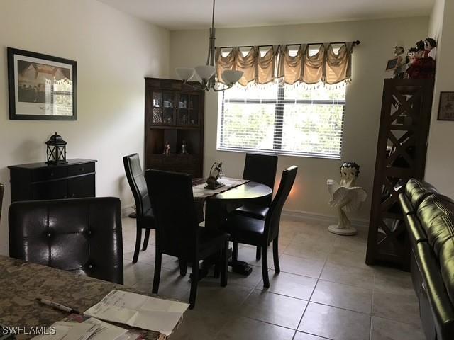 tiled dining room with baseboards and an inviting chandelier