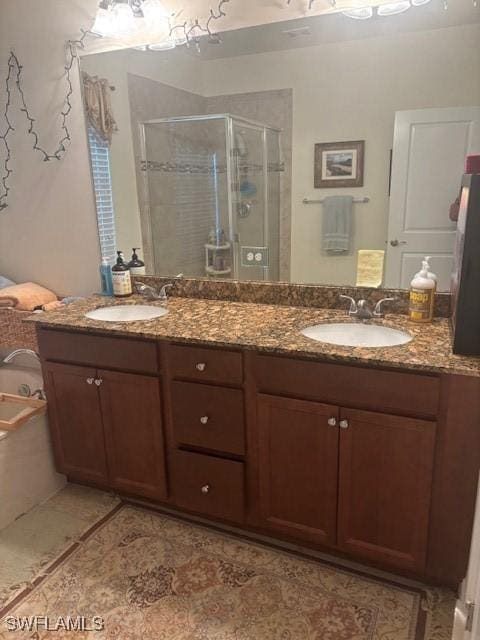 bathroom with double vanity, a stall shower, a sink, and tile patterned floors