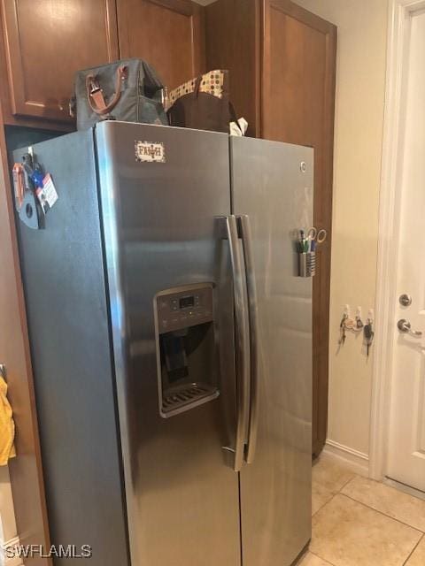 kitchen with brown cabinets, stainless steel refrigerator with ice dispenser, and light tile patterned flooring