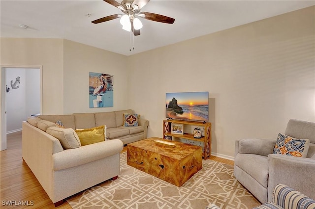 living room featuring light wood finished floors, ceiling fan, and baseboards