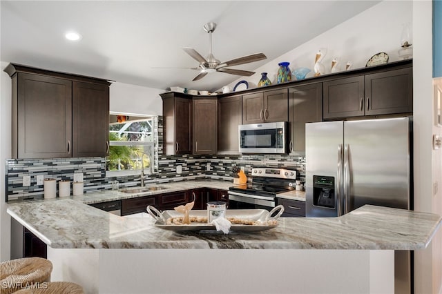 kitchen featuring appliances with stainless steel finishes, vaulted ceiling, a sink, and dark brown cabinets