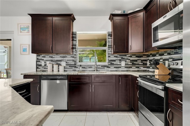 kitchen featuring tasteful backsplash, appliances with stainless steel finishes, light stone counters, marble finish floor, and a sink