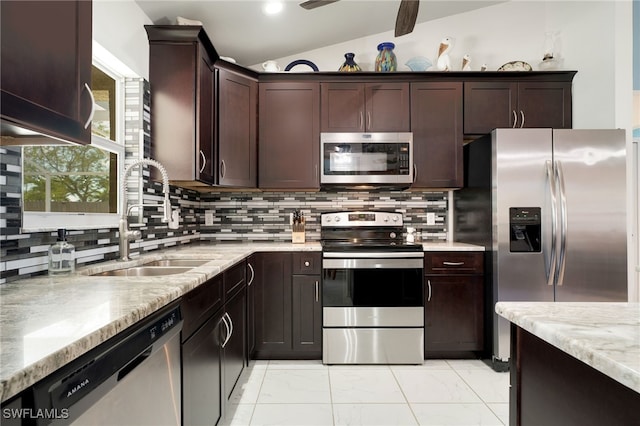 kitchen with a sink, vaulted ceiling, marble finish floor, appliances with stainless steel finishes, and backsplash