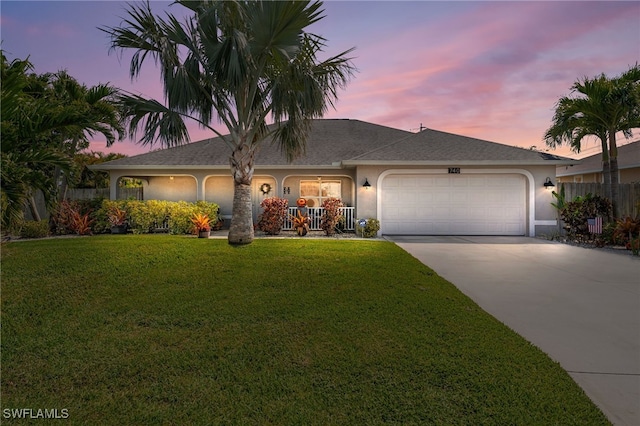 ranch-style house featuring a garage, concrete driveway, a lawn, fence, and stucco siding