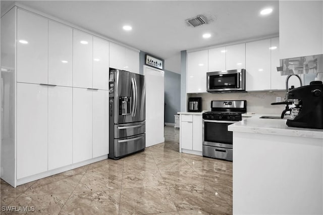 kitchen featuring visible vents, white cabinets, modern cabinets, appliances with stainless steel finishes, and a sink