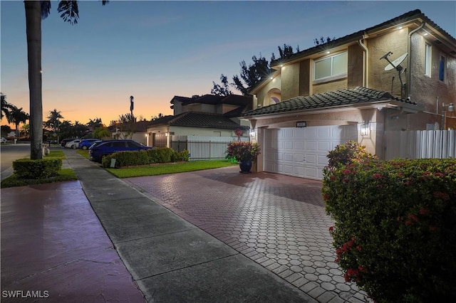 view of front of house featuring a garage, fence, decorative driveway, and stucco siding