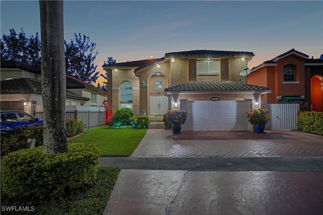 view of front of house with an attached garage, fence, decorative driveway, and stucco siding