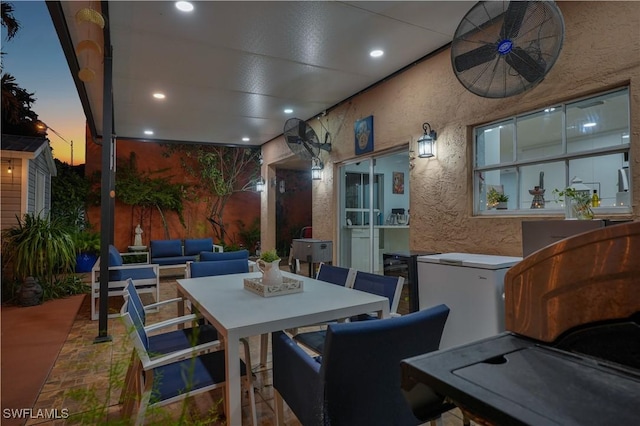 patio terrace at dusk with ceiling fan, an outdoor living space, and outdoor dining space