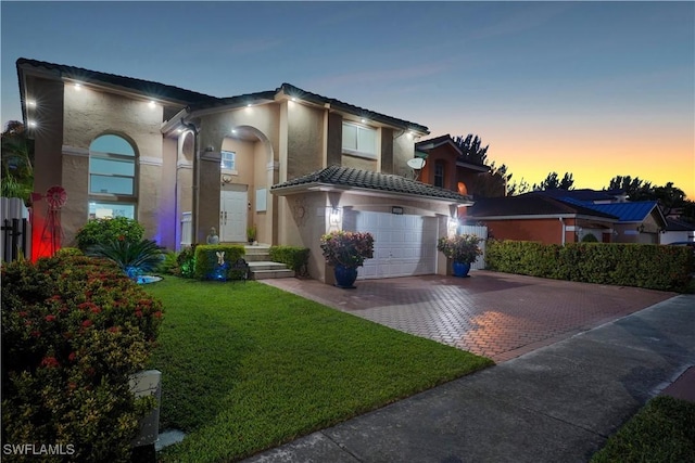 view of front of house featuring decorative driveway, a tile roof, stucco siding, an attached garage, and a front yard