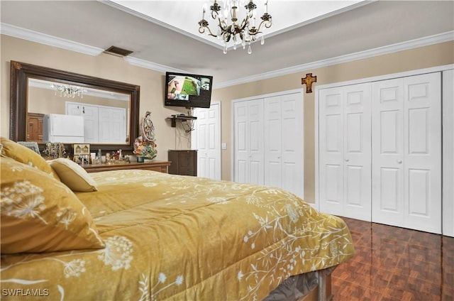 bedroom featuring ornamental molding, two closets, visible vents, and a notable chandelier