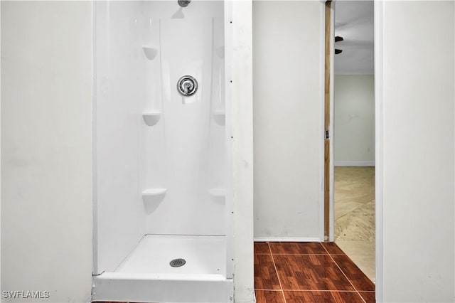 full bathroom featuring a stall shower, baseboards, and wood finished floors