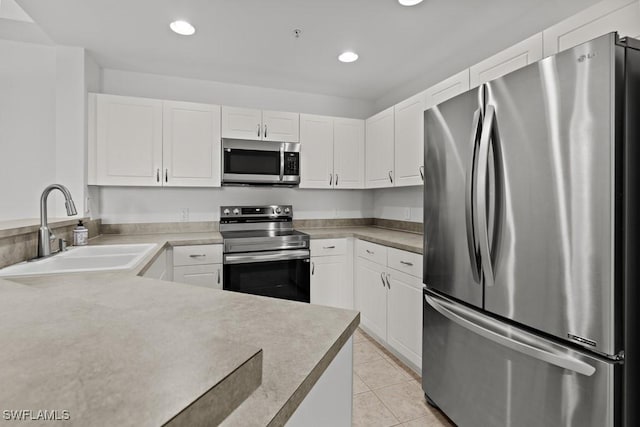 kitchen with stainless steel appliances, light countertops, white cabinetry, a sink, and light tile patterned flooring