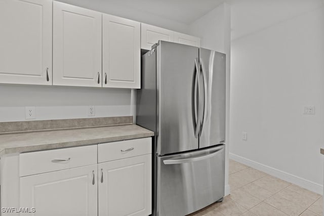 kitchen featuring freestanding refrigerator, light countertops, baseboards, and white cabinetry