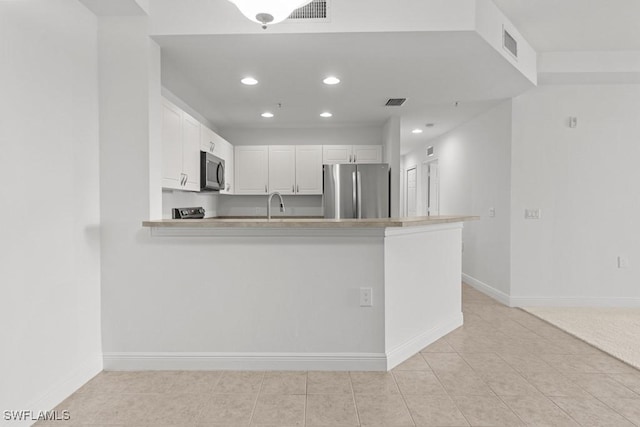 kitchen featuring visible vents, a peninsula, appliances with stainless steel finishes, and white cabinetry