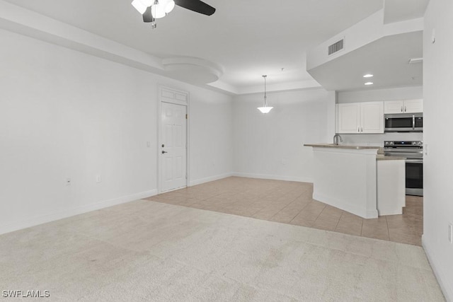 unfurnished living room featuring light tile patterned floors, light colored carpet, visible vents, baseboards, and a raised ceiling