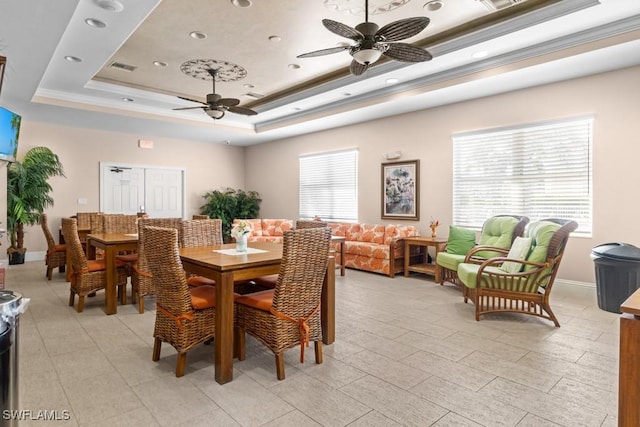 dining area featuring a tray ceiling, crown molding, visible vents, ceiling fan, and baseboards