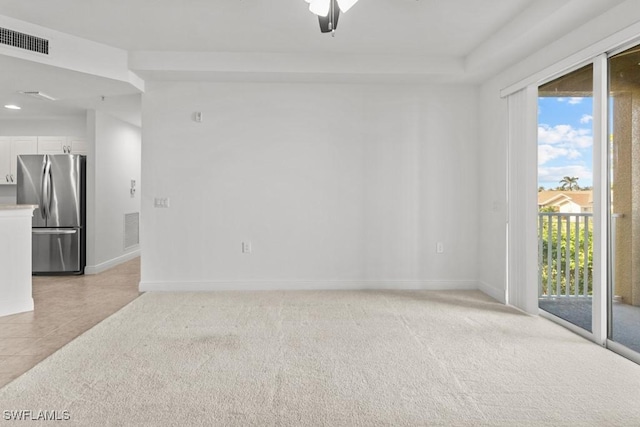 unfurnished room featuring light tile patterned floors, baseboards, visible vents, and light colored carpet