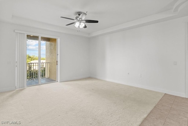 unfurnished room featuring ceiling fan, a raised ceiling, and baseboards