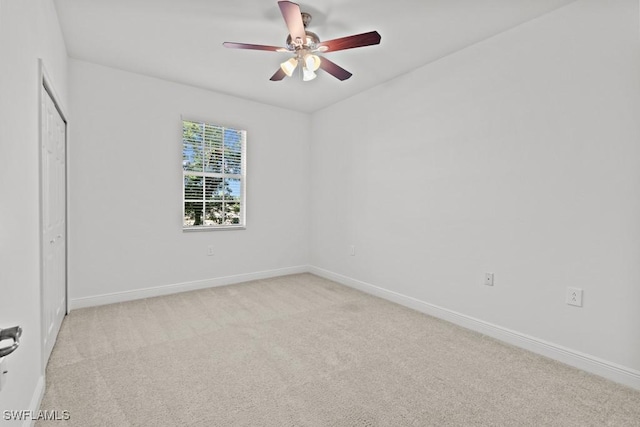 empty room featuring baseboards, a ceiling fan, and light colored carpet