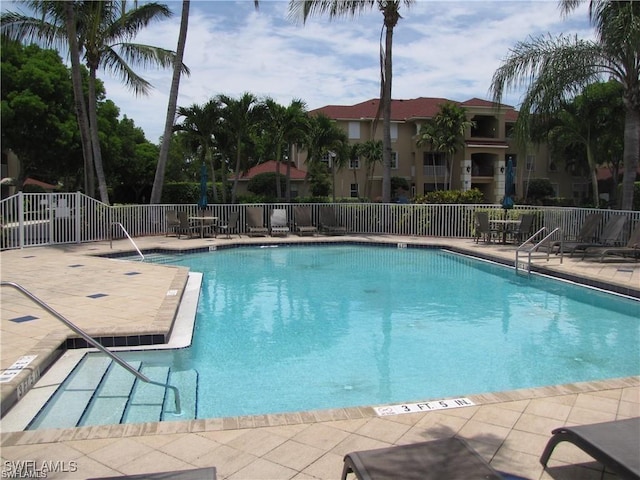 pool with a patio area and fence