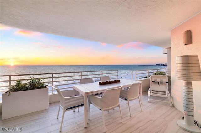 balcony with outdoor dining space and a water view