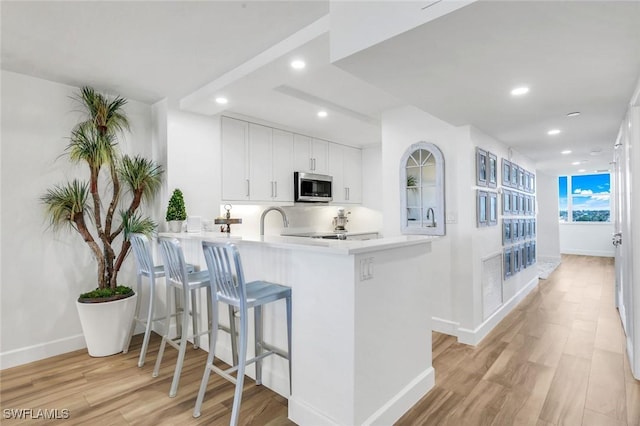 780 S Collier Blvd Unit 708, Marco Island, FL 34145 - kitchen with recessed lighting, light wood finished floors, stainless steel microwave, baseboards, and a peninsula