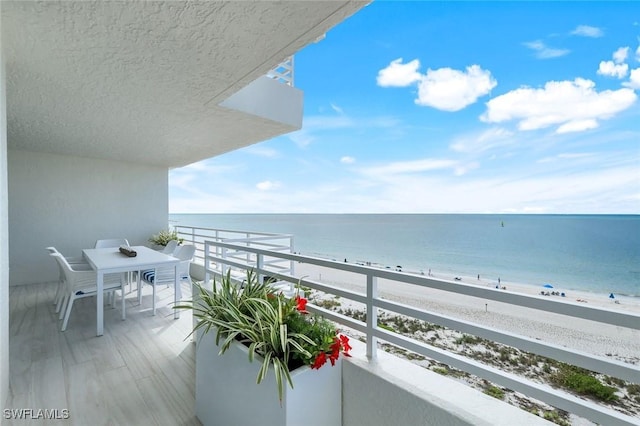 balcony with a water view and a view of the beach