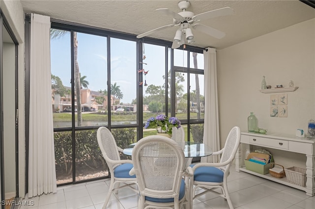 dining area with ceiling fan, light tile patterned floors, a textured ceiling, a sunroom, and expansive windows