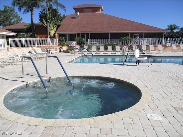 pool with a patio area, a hot tub, and fence