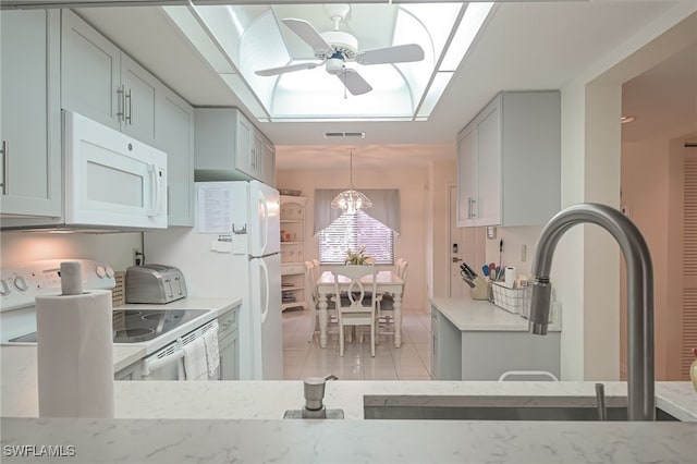 kitchen featuring a toaster, light tile patterned floors, visible vents, white appliances, and ceiling fan with notable chandelier